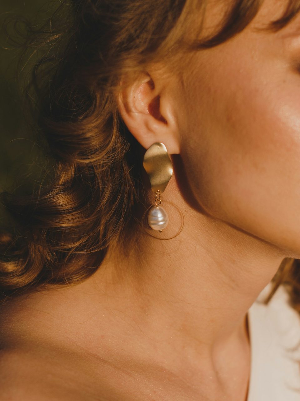A gold drop earring worn with flowing hair
