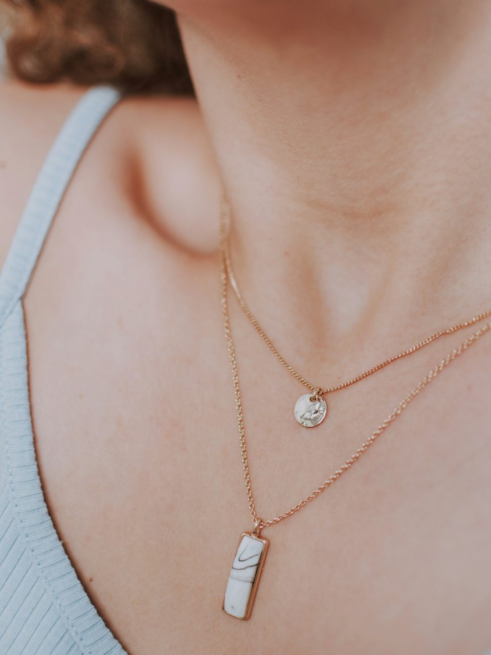 Layered fine pendants on a neckline