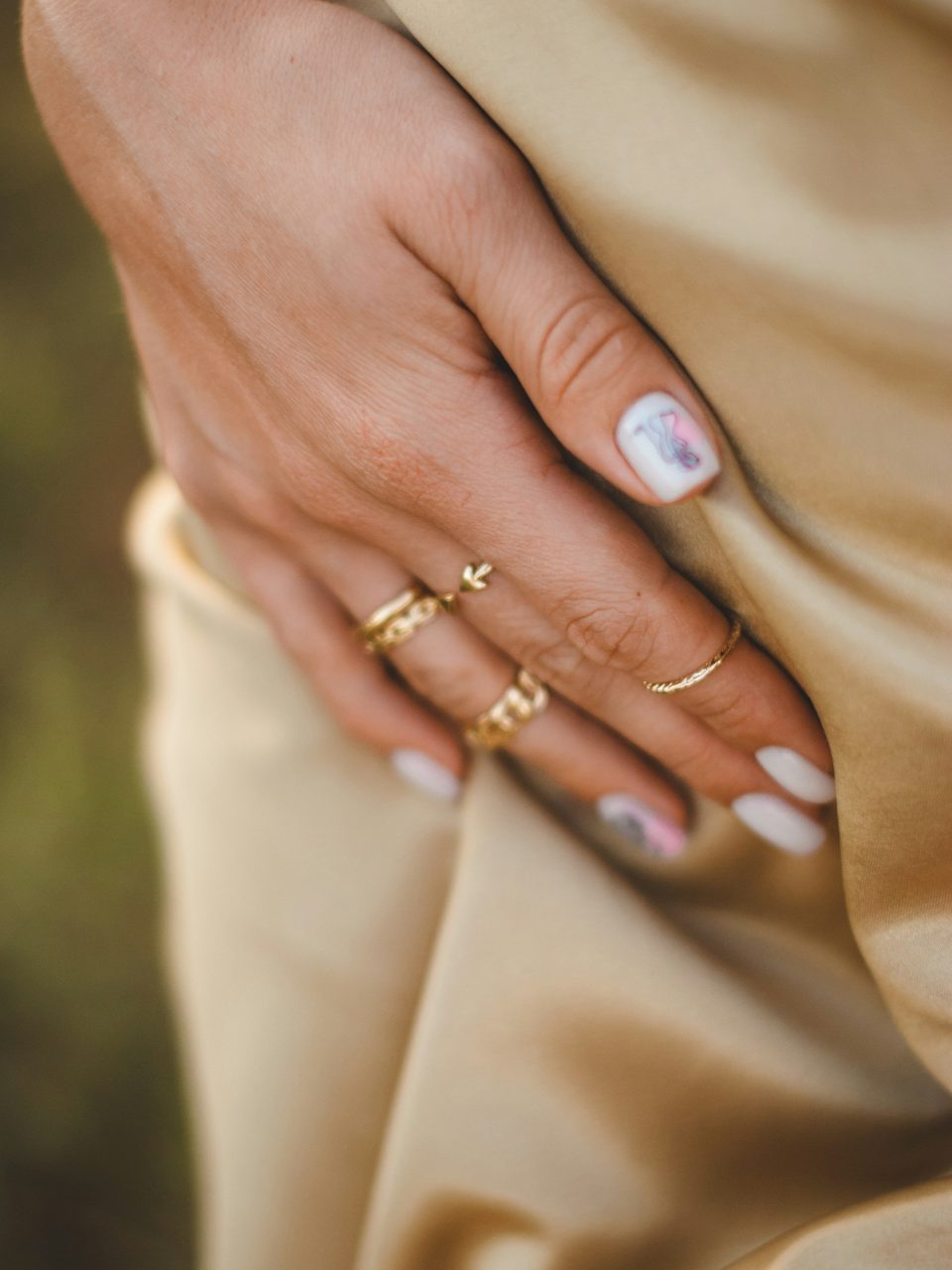 Stacked fine rings on a hand resting on satin