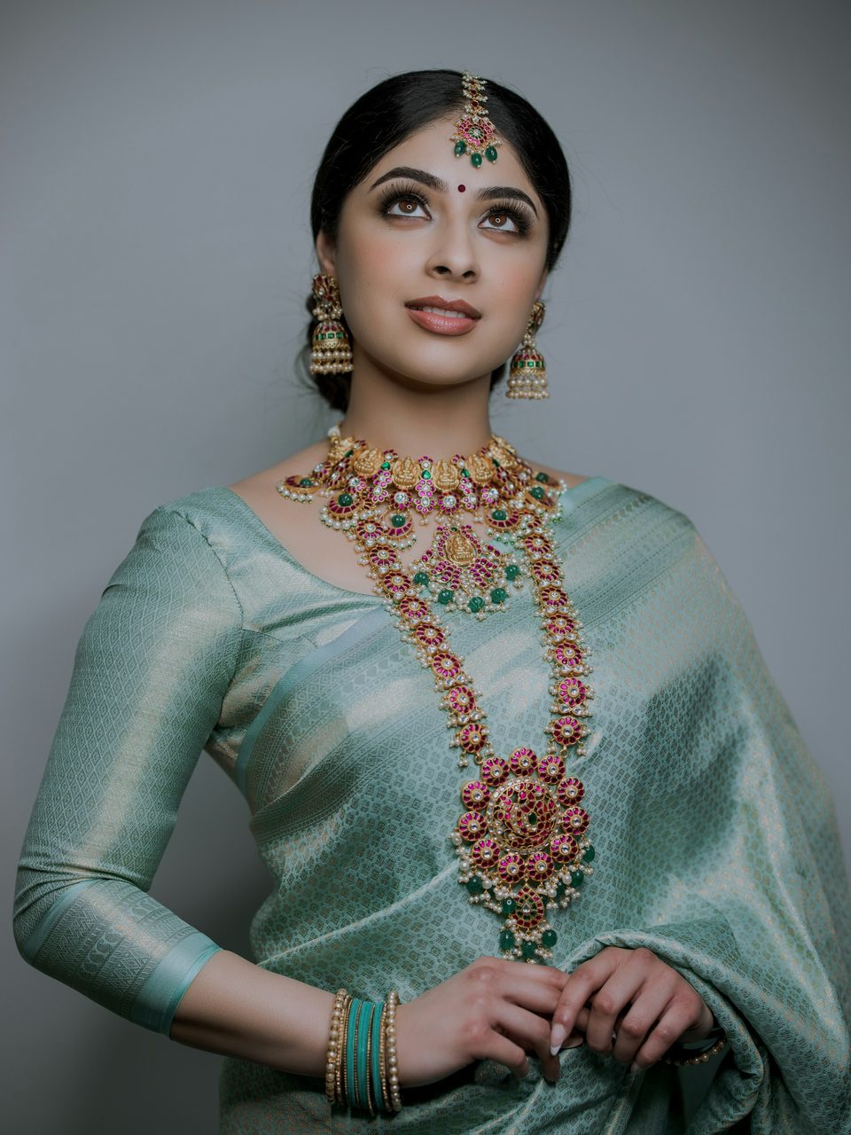 A woman in a mint saree wearing a long necklace set