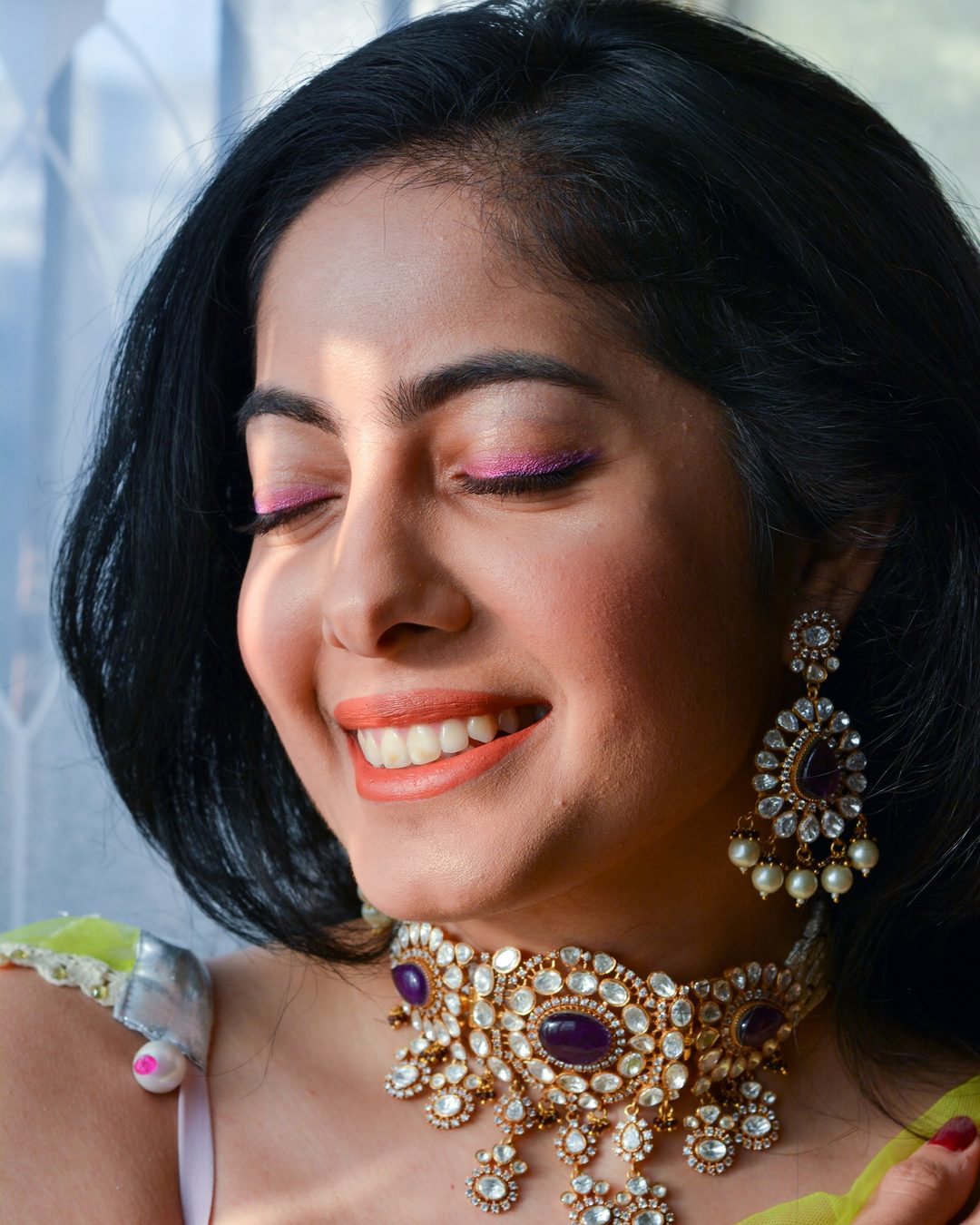 A smiling woman wearing a jewelled choker and statement earrings