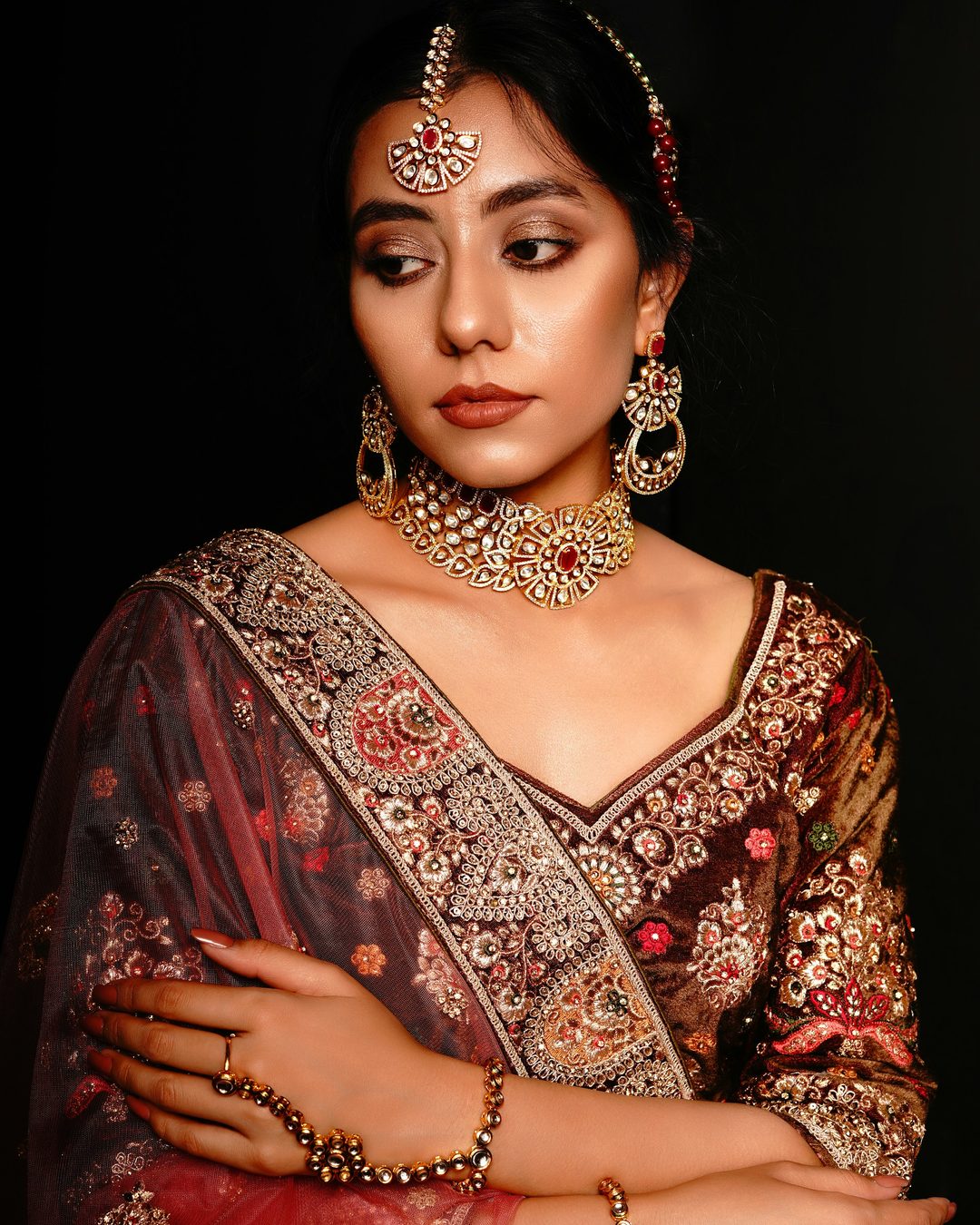 A woman in a festive saree wearing layered necklaces and earrings
