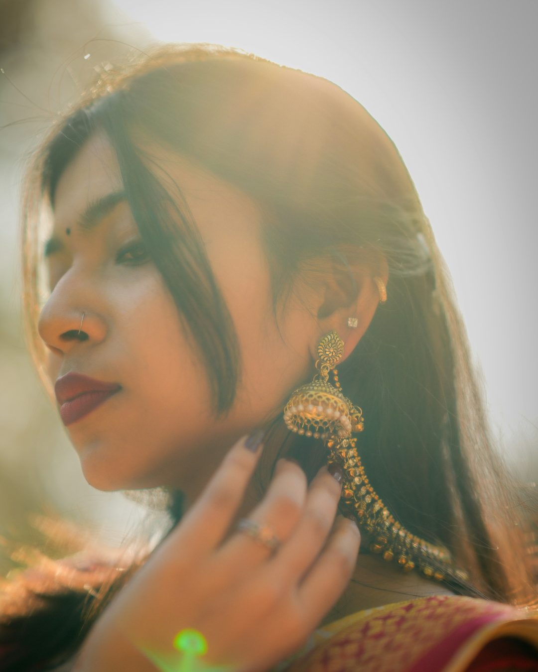 A woman in golden evening light wearing gold drop earrings