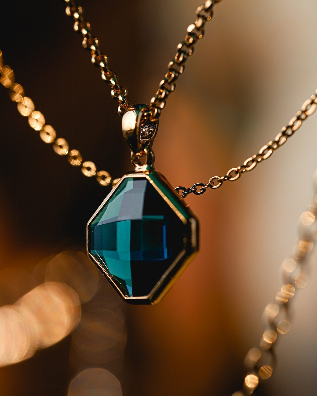 A deep teal pendant glowing against warm evening light